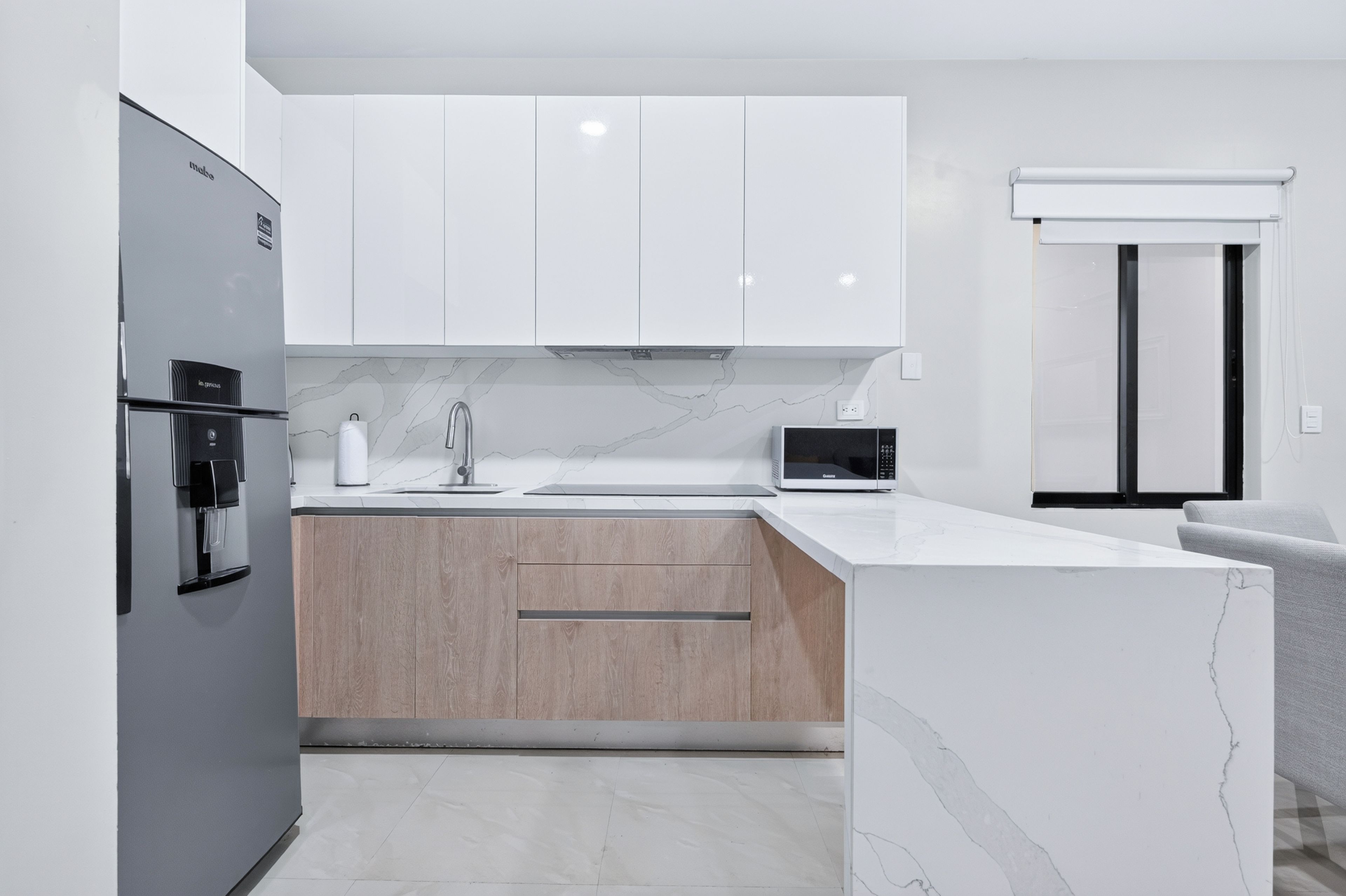 A modern kitchen with white cabinetry, a marble countertop, and a built-in oven.
