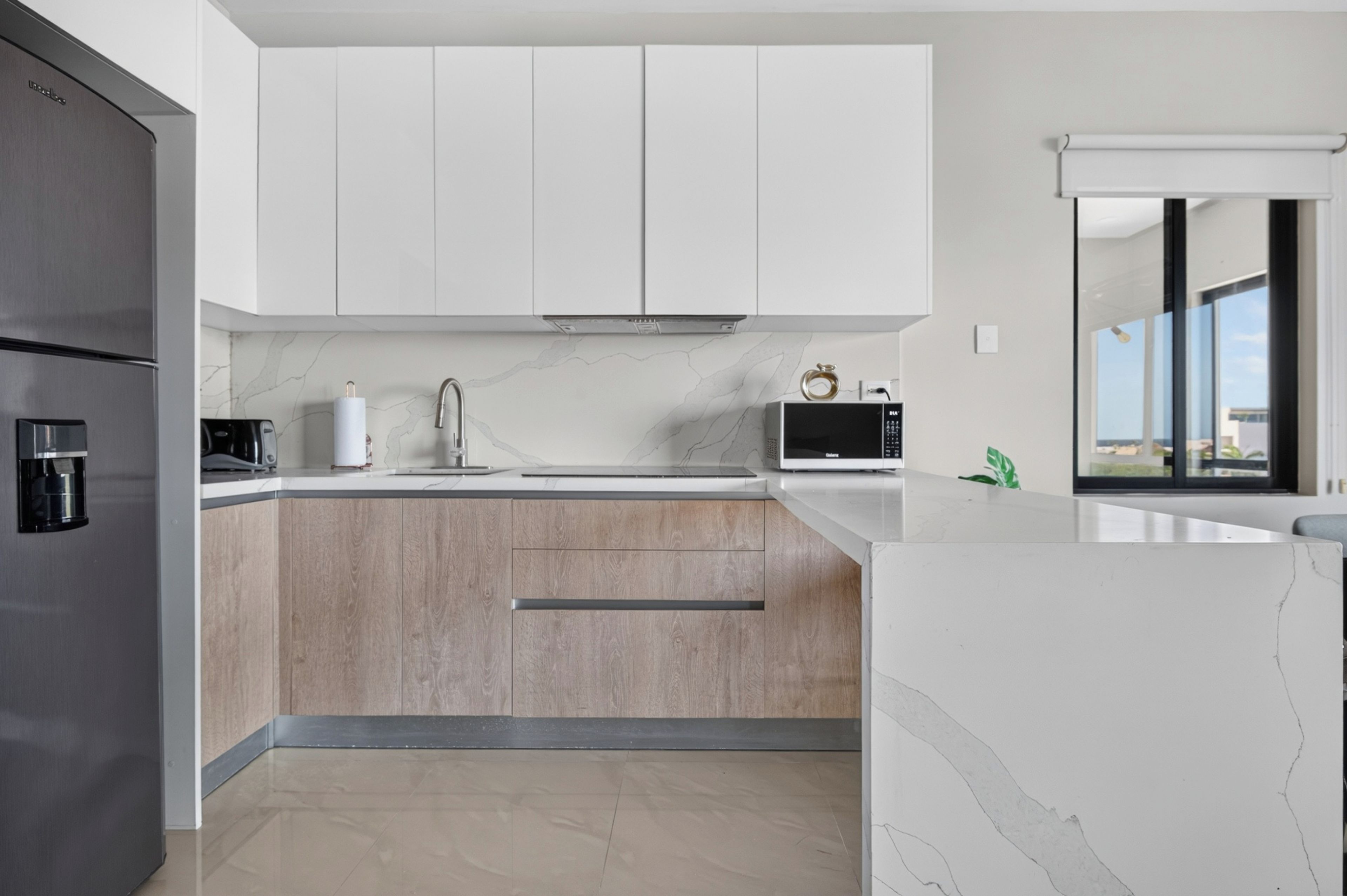 Una cocina moderna con un refrigerador integrado, un microondas y una cafetera.