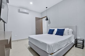 Quarto moderno com cama, mesa de cabeceira e luminária pendente.