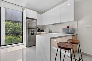 Una cocina moderna con una isla grande, electrodomésticos de acero inoxidable y vistas al exterior.