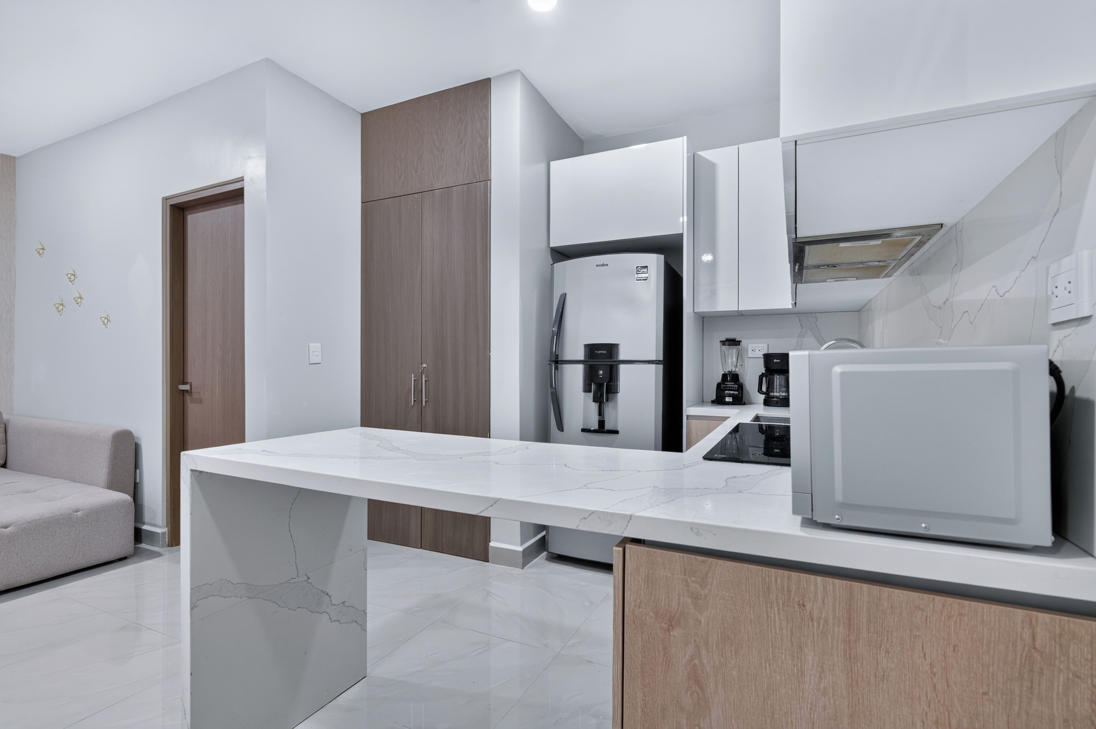 Una cocina moderna con encimera de mármol, electrodomésticos integrados y un armario de madera.
