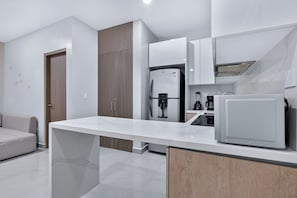 Cozinha moderna com bancada de mármore, eletrodomésticos embutidos e armário de madeira.