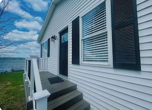 A house with a front porch, a door, and a window with shutters.