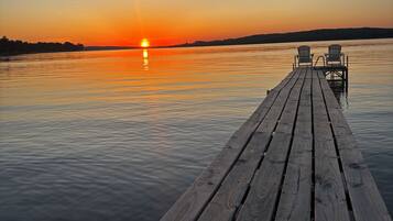 Une jetée en bois s’étendant sur une étendue d’eau calme, avec un coucher de soleil en arrière-plan.