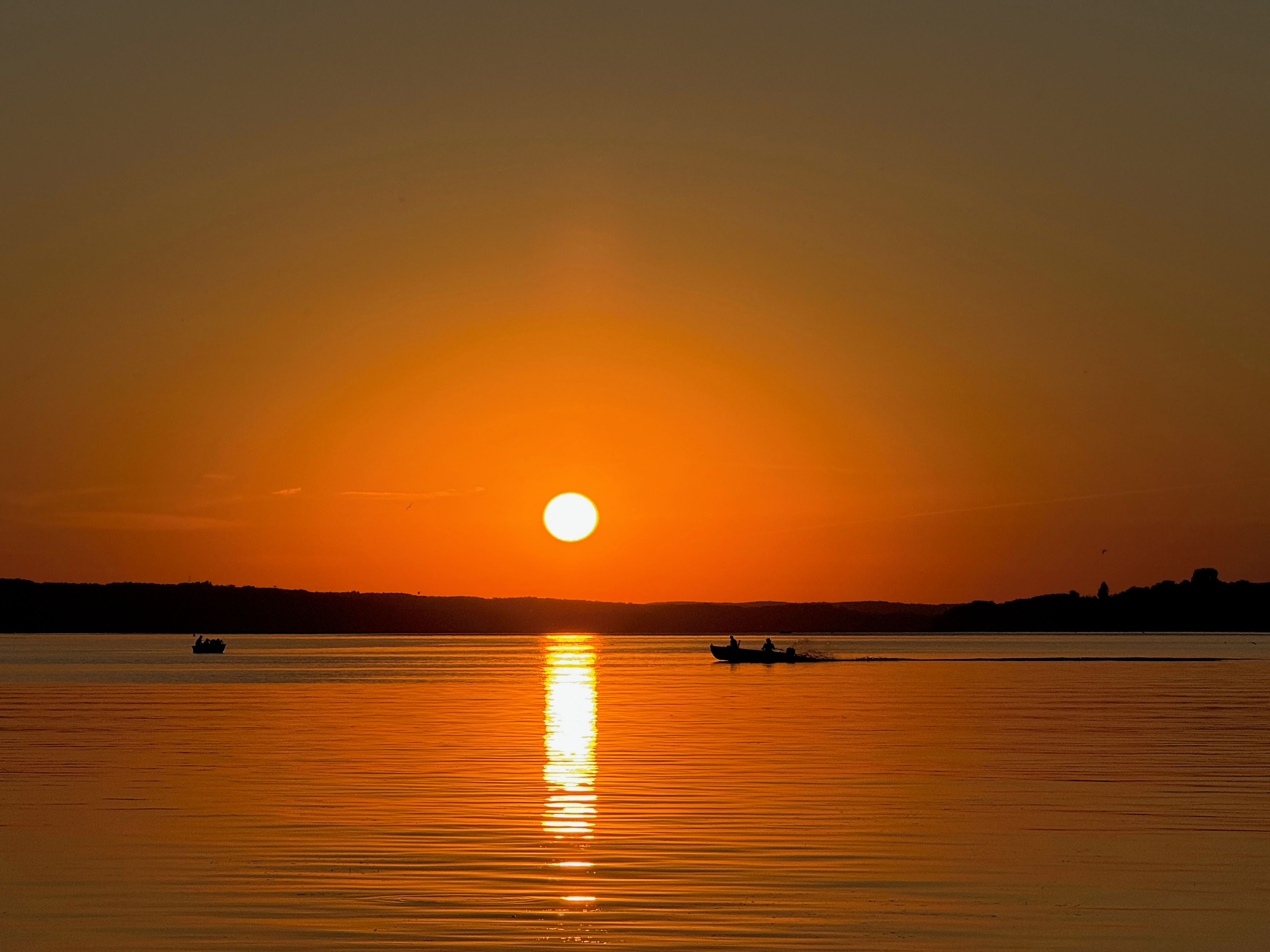 A sunset over a calm body of water with boats.