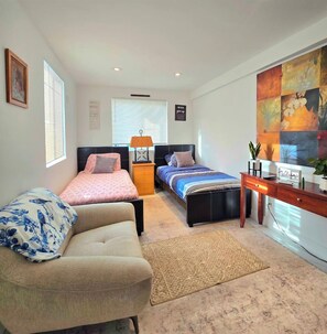 Une chambre à coucher avec un lit, un canapé, un bureau et un tableau au mur.