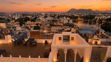 Una terraza en la azotea con vistas a un paisaje urbano y un río al atardecer.