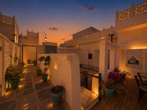 A courtyard with potted plants, a staircase, and a wall with a mural. - Hari Priya Resort Udaipur (Udaipur)