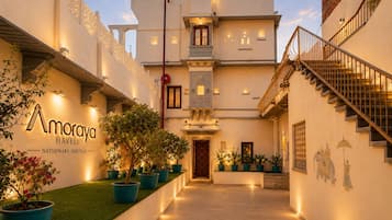 Un edificio tradicional con entrada central, plantas en macetas y una escalera a la derecha.