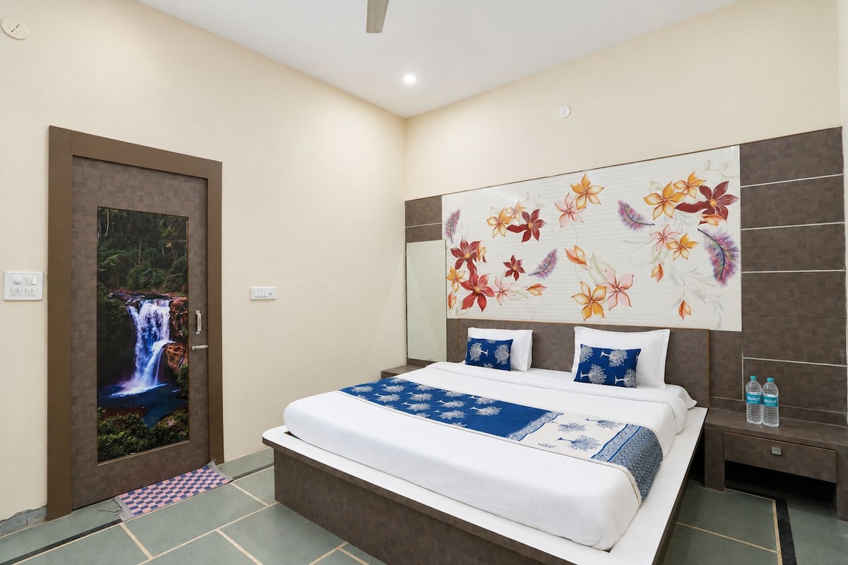 Habitación de hotel con cama, mesita de noche, una obra de arte en la pared y una puerta con una imagen de cascada.