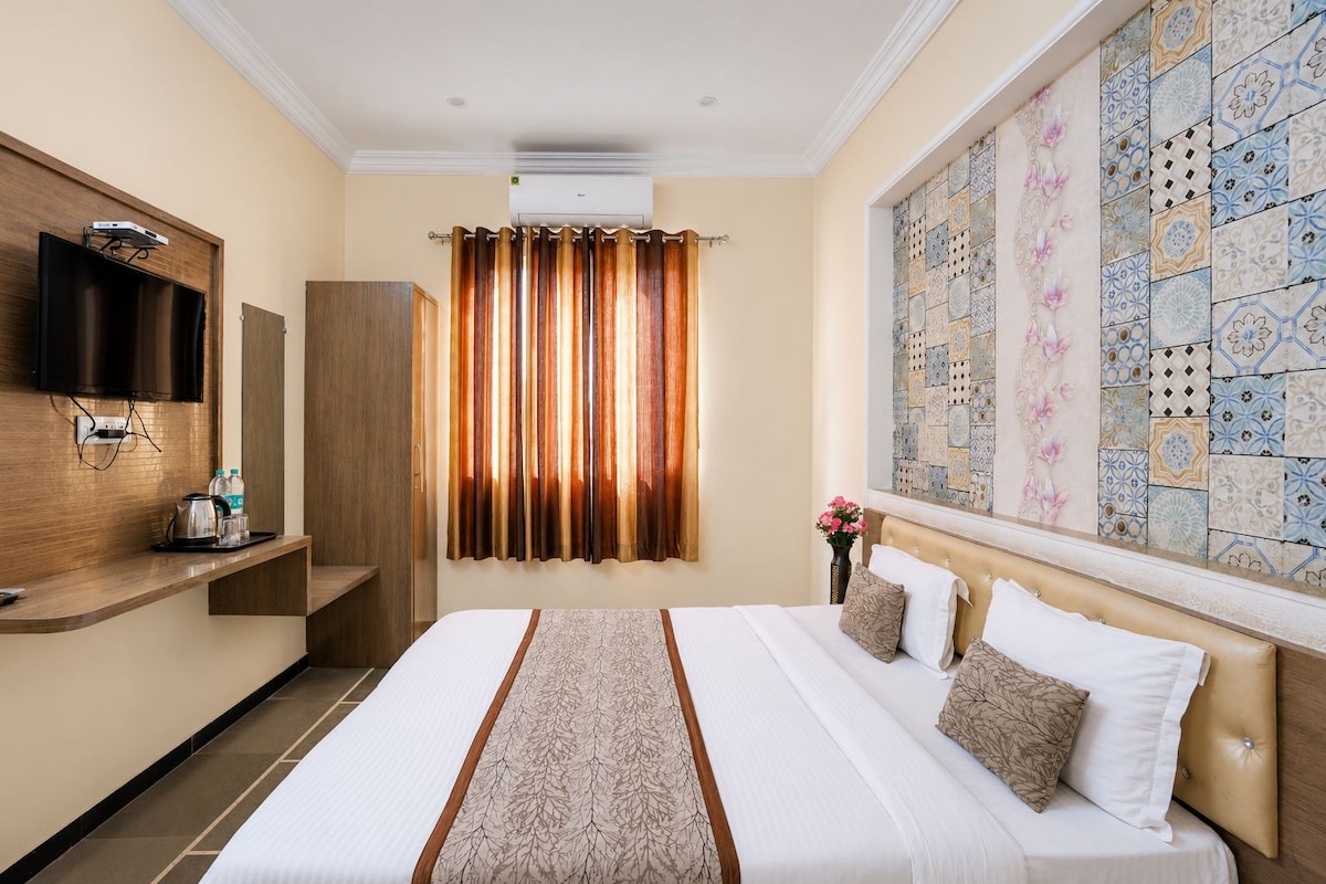 Habitación de hotel con cama, televisor montado en la pared, pantalla plana, aire acondicionado instalado en la pared y pared decorada con azulejos.
