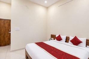 Una habitación de hotel con una cama grande, cabecero de madera y un corredor decorativo rojo.