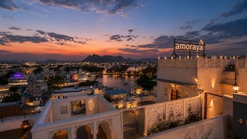 A hotel with a view of a cityscape and a river at dusk.