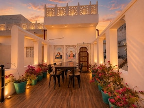 A dining area with a table and chairs, potted plants, and decorative wall art. - Hari Priya Resort Udaipur (Udaipur)