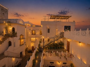A traditional courtyard with a staircase, white walls, and a sunset sky. - Hari Priya Resort Udaipur (Udaipur)