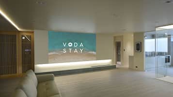 Un área de recepción moderna con un mural grande en la pared, un mostrador de recepción y una zona de estar.