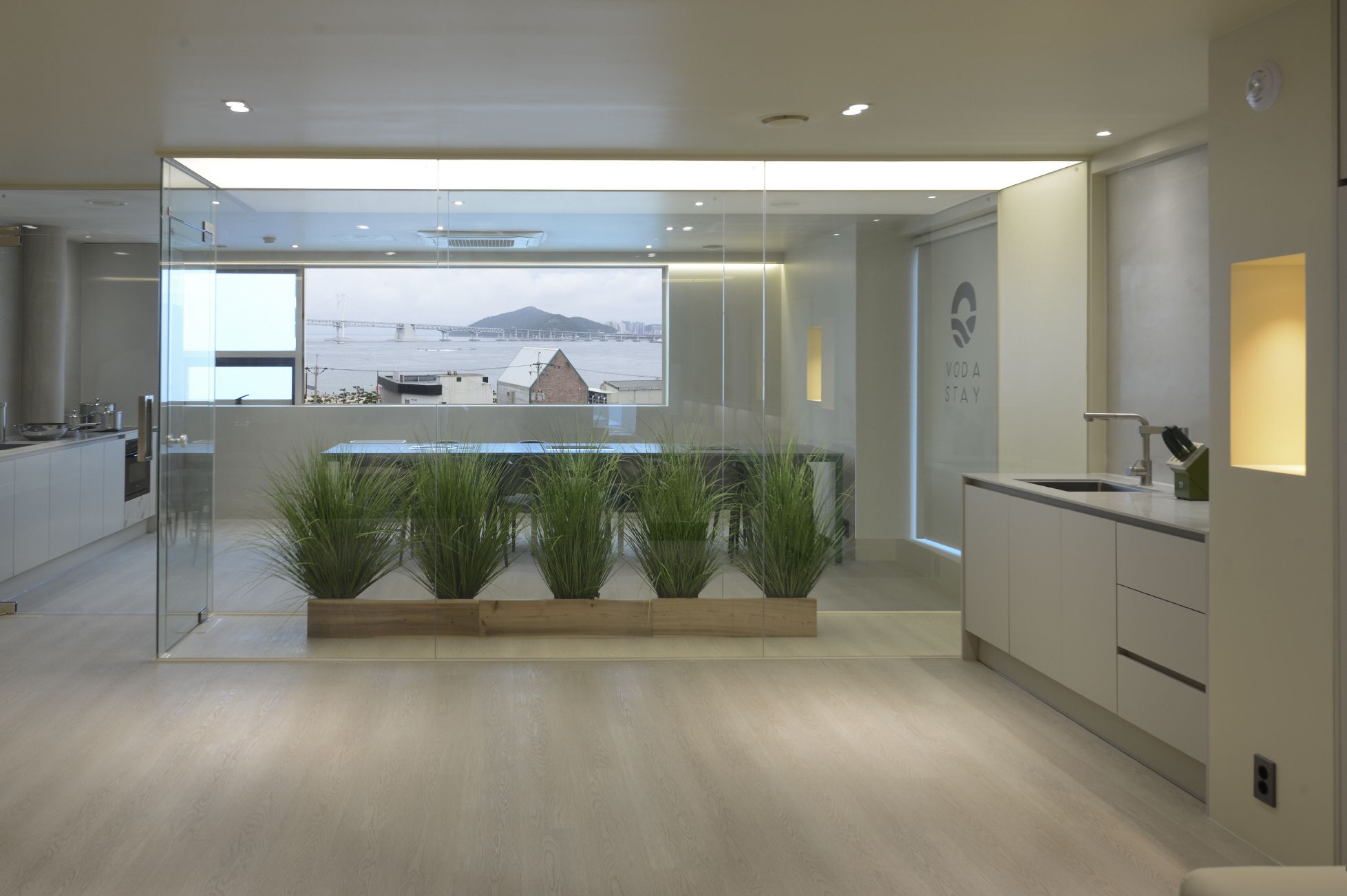 Cocina moderna con separador de vidrio, vista a un puente y un letrero que dice 'VODASTAY'.