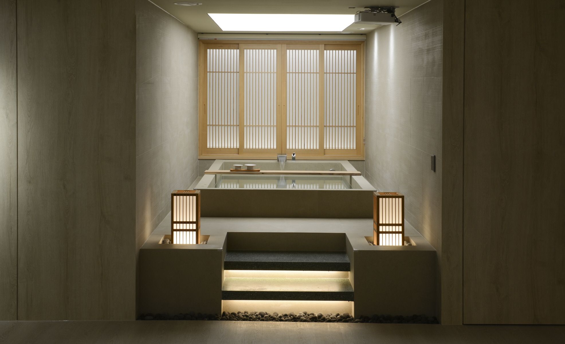 Un baño minimalista con lavamanos empotrado, una ventana con persianas verticales y un pequeño escalón que lleva a una zona con guijarros.