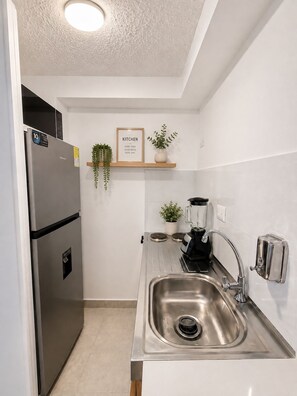 A compact kitchen with a stainless steel refrigerator, a sink, a toaster, and a blender on the counter. - DORÉ 26 | Modern accommodations near El Dorado (Bogotá)
