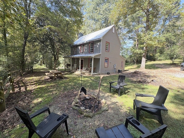 A house with a porch, a fire pit, and outdoor seating. - Farmhouse and Bunkhouse on 14 Wooded Acres with a Private Pond and Dock (Ronda)