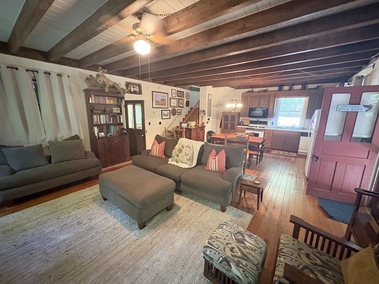 A cozy living room with a sofa, ottoman, and a bookshelf.