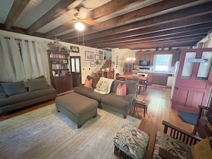 A cozy living room with a sofa, ottoman, and a bookshelf. - Farmhouse and Bunkhouse on 14 Wooded Acres with a Private Pond and Dock (Ronda)