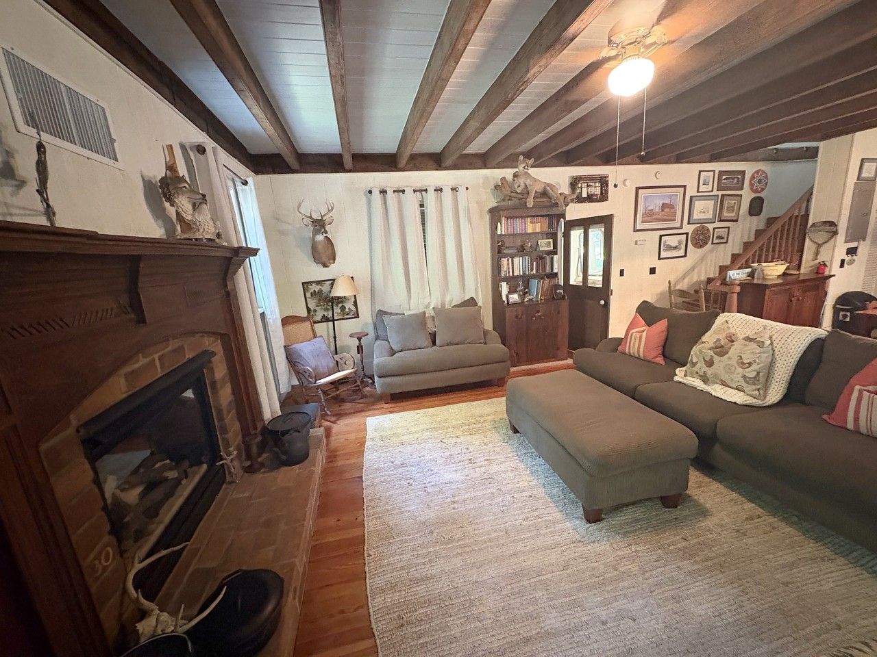 A cozy living room with a fireplace, a sofa, a coffee table, and a bookshelf.