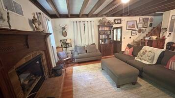 A cozy living room with a fireplace, a sofa, a coffee table, and a bookshelf.