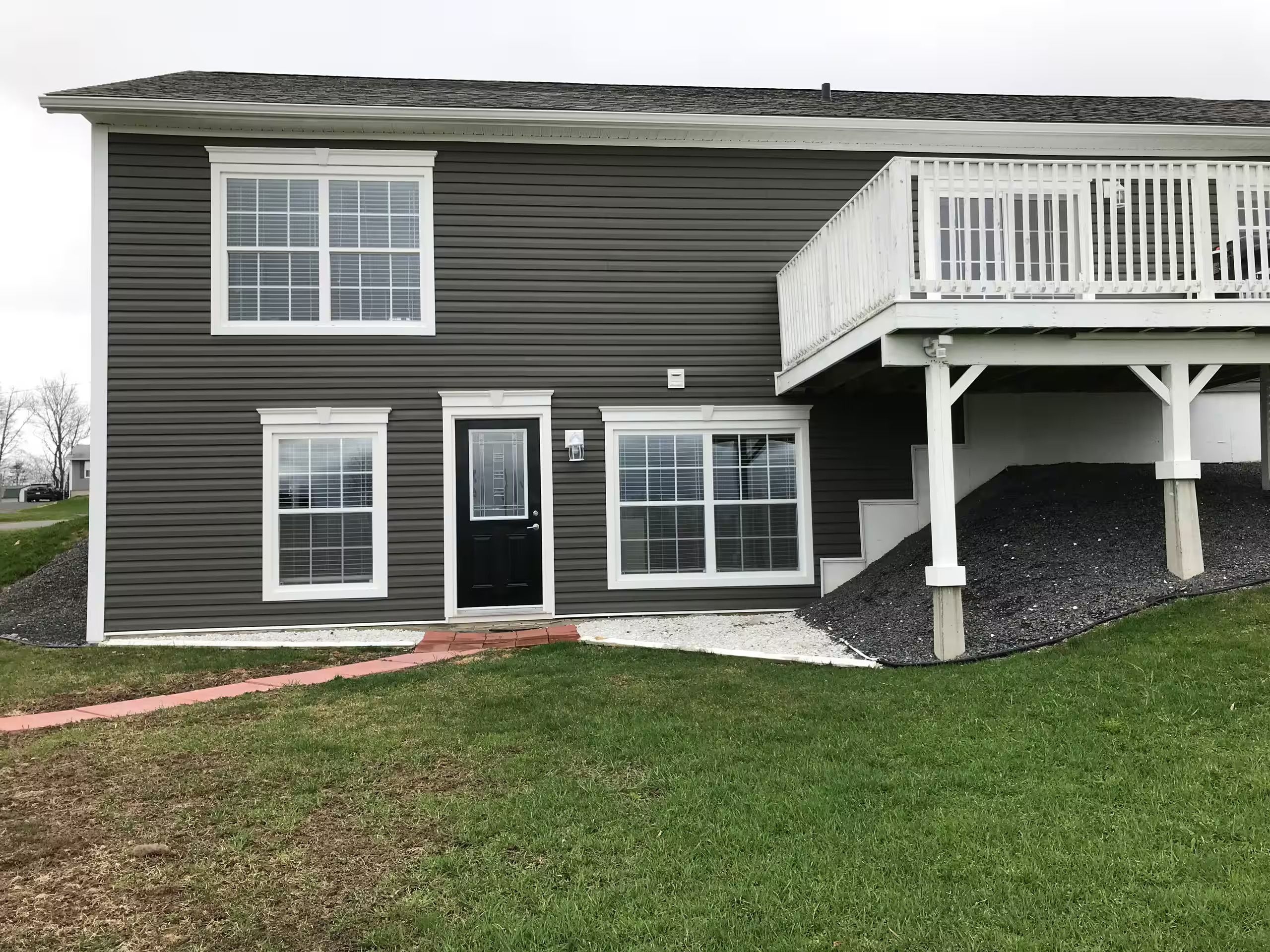 A two-story house with a front porch, a black door, and a small front yard.
