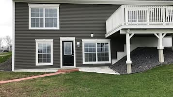 A two-story house with a front porch, a black door, and a small front yard.
