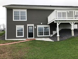 A two-story house with a front porch, a black door, and a small front yard.