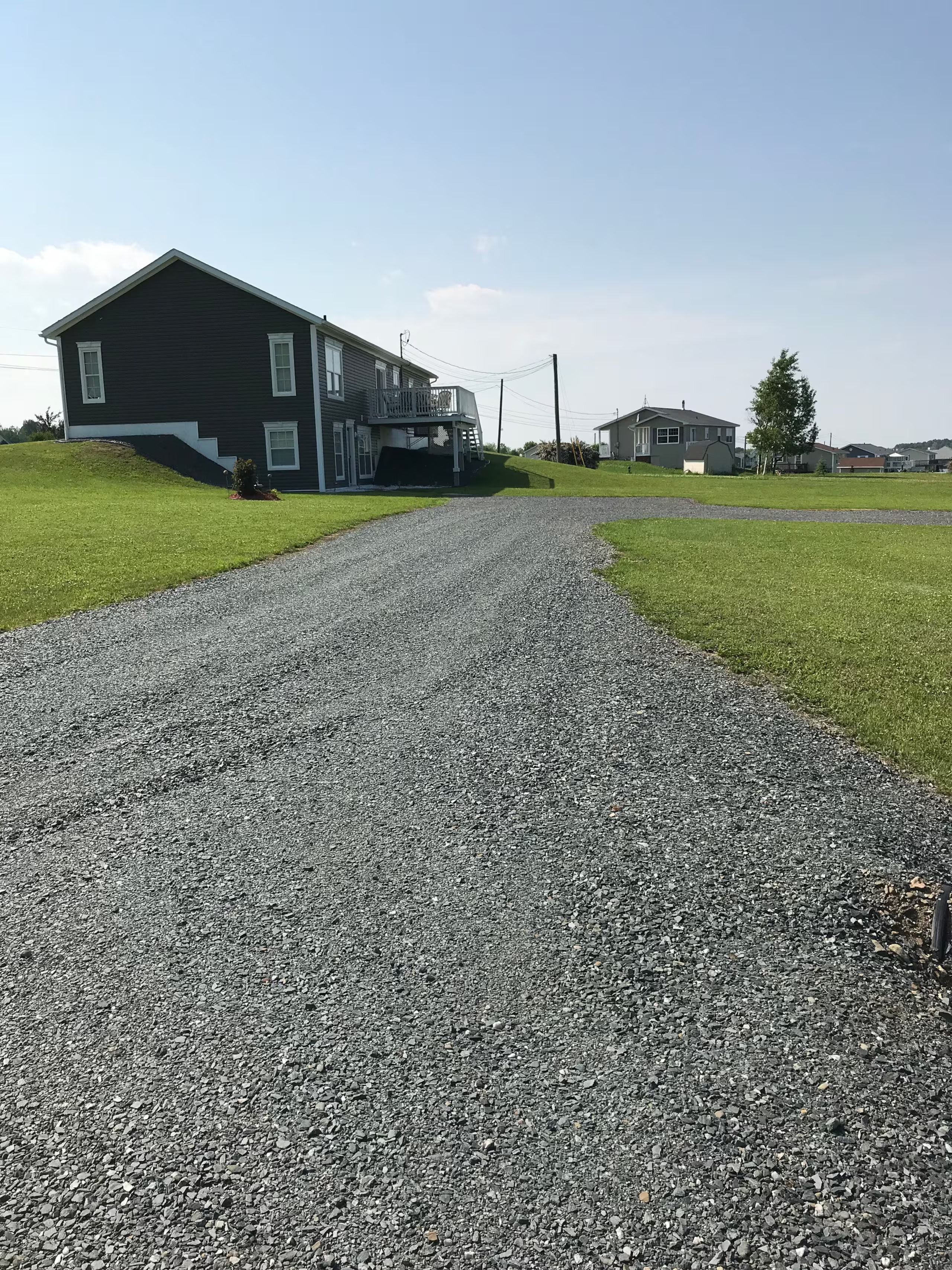 A residential driveway leading to a two-story house with a balcony.