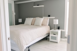 Un dormitorio con cama, mesitas de noche y un velador.