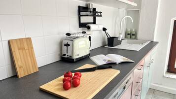 Una cocina moderna con un tostador, una tabla de cortar con tomates y un libro de cocina sobre la encimera.