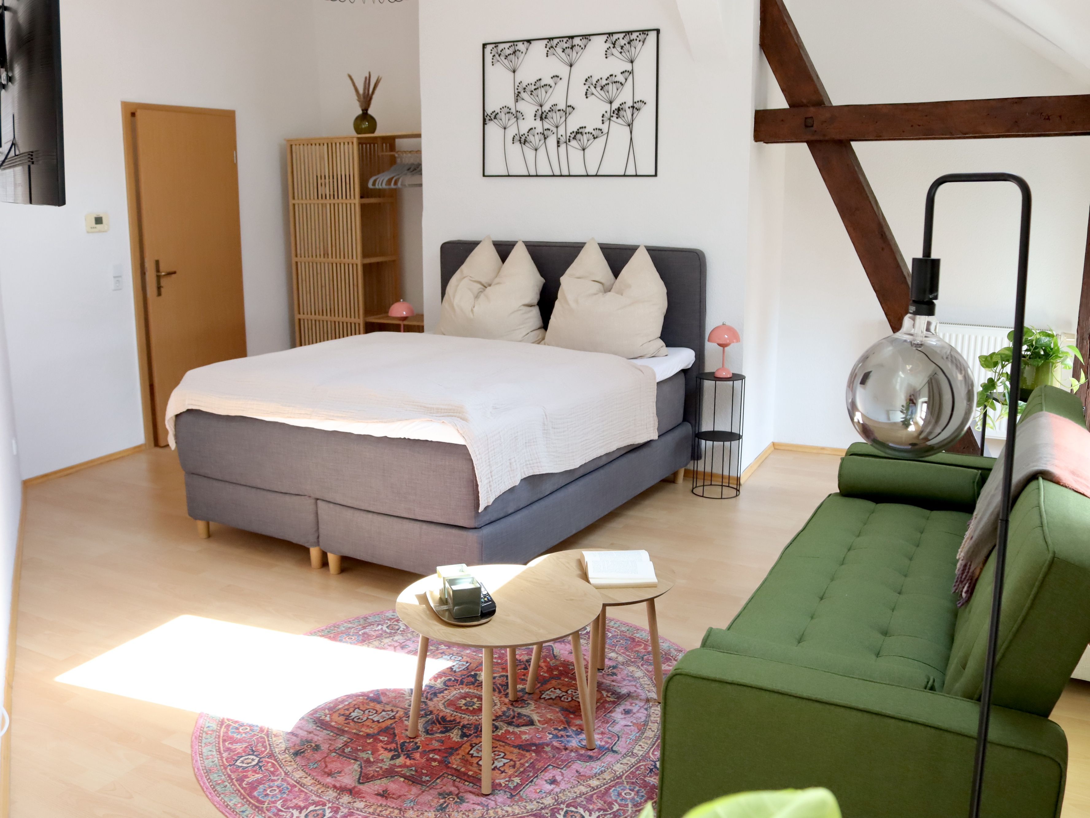 Ein Schlafzimmer mit einem Bett, einem Nachttisch, einer Lampe und einem grünen Sofa.
