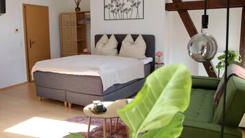 Un dormitorio con cama, mesita de noche, lámpara y sofá verde.
