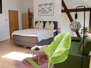 Un dormitorio con cama, mesita de noche, lámpara y sofá verde.