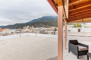 A rooftop terrace with a view of a mountainous landscape, a covered seating area, and a white railing. - PENTHOUSE IN LOUTRAKI (Loutraki)