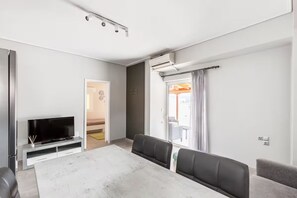 A modern living room with a dining table, a flat-screen TV, and a seating area. - PENTHOUSE IN LOUTRAKI (Loutraki)