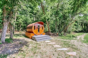 A wooden cabin with a curved roof, built into a forested area with a dirt path leading to it. - Gettysburg Queen Suite for 4 - Fireplace, Sofa Bed, Hot Tub & Sauna (Gettysburg)