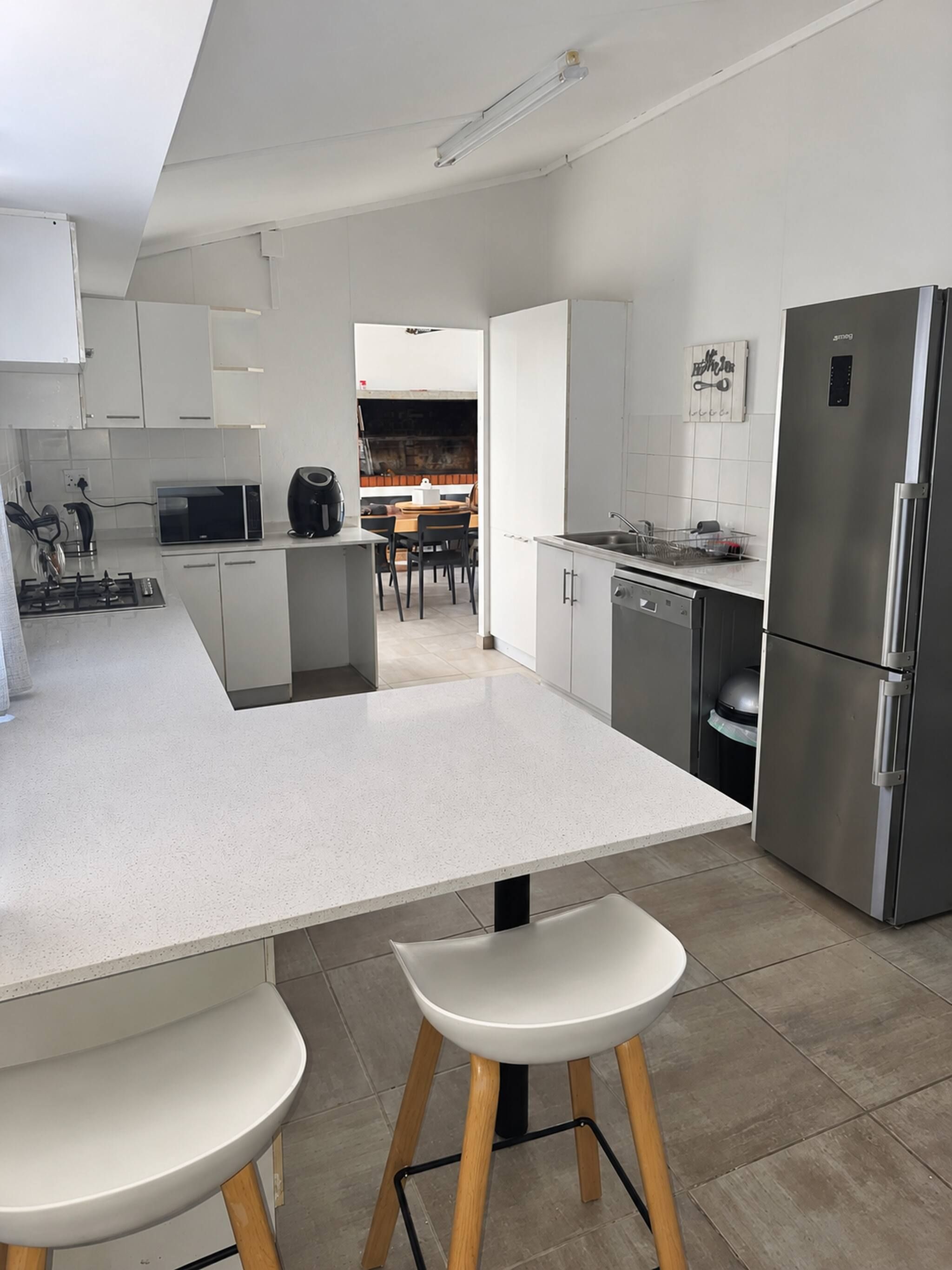 Une cuisine moderne avec des meubles blancs, un réfrigérateur en acier inoxydable et un îlot central doté de tabourets.