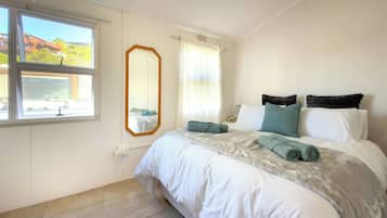 Une chambre à coucher avec un lit, un grand miroir, une fenêtre et une vue sur un train.