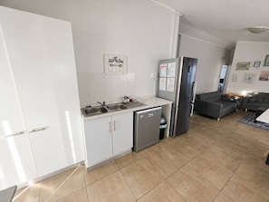 A modern kitchen with white cabinets, a stainless steel dishwasher, and a refrigerator.