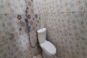 Un bany amb vàter, dutxa i una paret amb un dibuix circular.