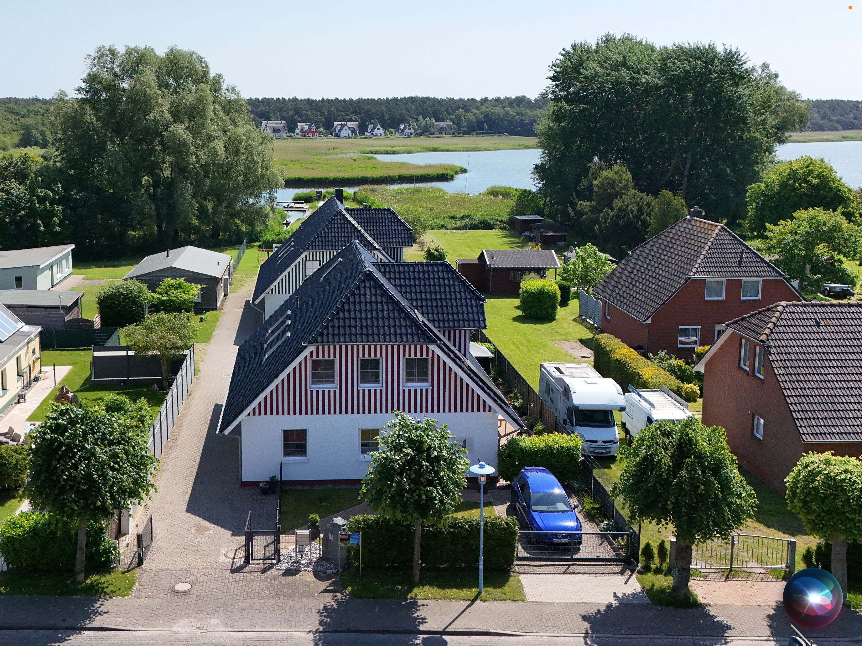 A residential area with houses, a lake, and a parked camper van.