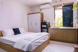 A bedroom with a bed, a wardrobe, a small kitchenette, and a window with a view. - Homestay Adam Hà Đông (Kien Hung)