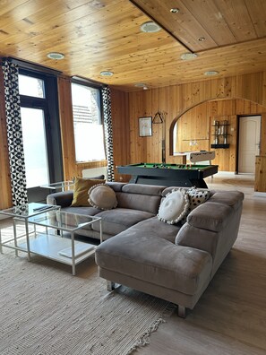A cozy living room with a sectional sofa, a pool table, and a glass coffee table. - Charming house for 8 people, with a pool table and an enclosed garden (Sacquenville)