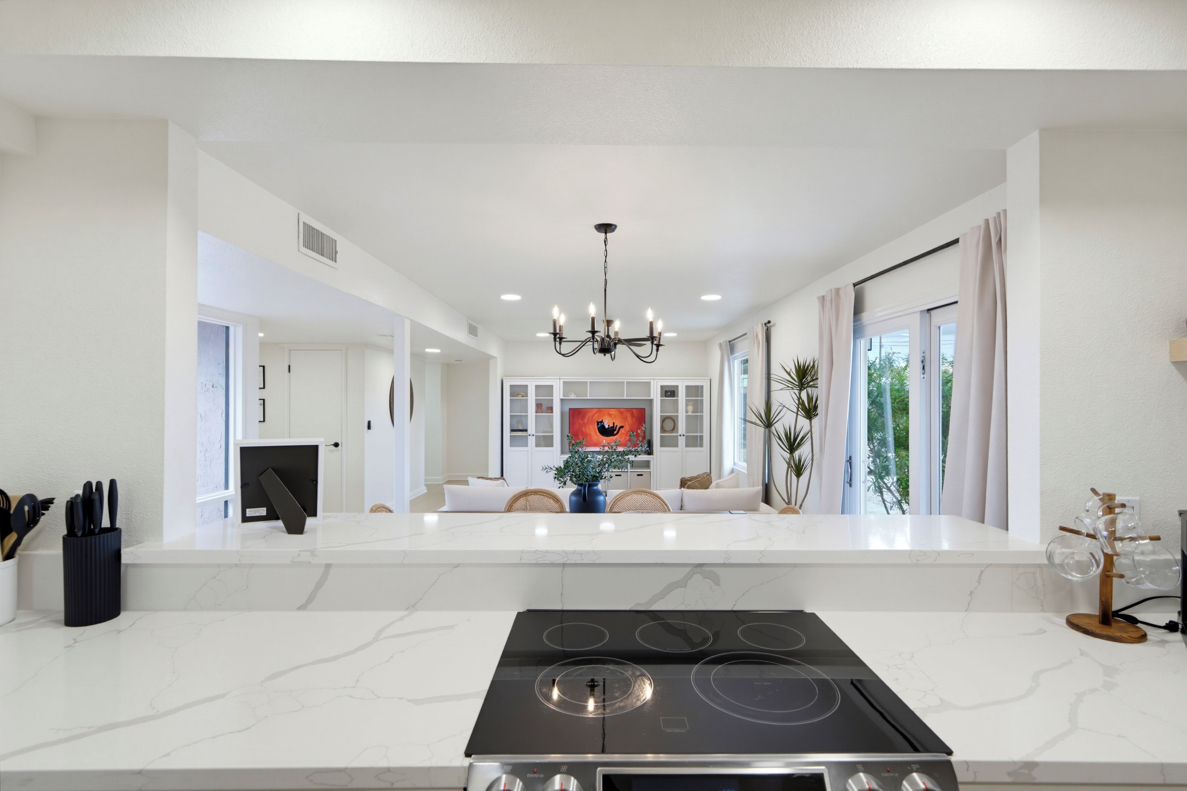 A modern kitchen with a central island, a built-in stove, and a dining area with a sofa and table.
