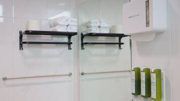 Een badkamer met handdoekrekken, een handdroger en groene flessen shampoo en conditioner.