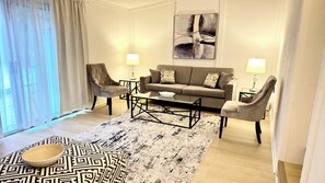 A modern living room with a sofa, two armchairs, a coffee table, and a patterned rug. - Bright & Cozy Retreat Near Shops & Subway (North York)